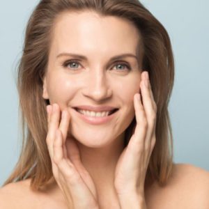 Head shot portrait smiling woman touching perfect smooth face skin